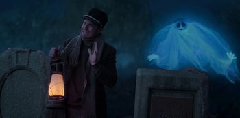 Movie still from “Muppets Haunted Mansion” (2021), directed by Kirk R. Thatcher – A man holding a lantern in front of a statue; Medium shot, Low angle