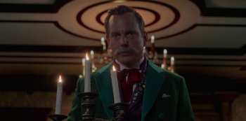 Movie still from “Muppets Haunted Mansion” (2021), directed by Kirk R. Thatcher – A man in a green jacket holding candles; Close Up shot, Low angle