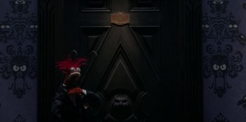Movie still from “Muppets Haunted Mansion” (2021), directed by Kirk R. Thatcher – A stuffed animal in front of a door; Medium shot, Low angle