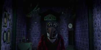 Movie still from “Muppets Haunted Mansion” (2021), directed by Kirk R. Thatcher – A person wearing a bird mask in front of a clock; Wide shot, High angle