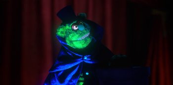 Movie still from “Muppets Haunted Mansion” (2021), directed by Kirk R. Thatcher – A stuffed animal dressed in a suit and top hat; Medium shot, Low angle
