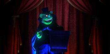 Movie still from “Muppets Haunted Mansion” (2021), directed by Kirk R. Thatcher – A person dressed as a frog in a stage setting; Medium shot, Low angle