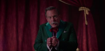Movie still from “Muppets Haunted Mansion” (2021), directed by Kirk R. Thatcher – A man in a green suit and a red bow tie; Medium shot, Low angle