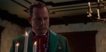 Movie still from “Muppets Haunted Mansion” (2021), directed by Kirk R. Thatcher – A man in a green jacket and a red tie; Close Up shot, Over the shoulder angle