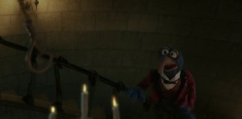 Movie still from “Muppets Haunted Mansion” (2021), directed by Kirk R. Thatcher – A muppet holding a stick in front of candles; Medium shot, Low angle