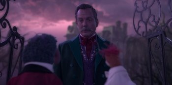 Movie still from “Muppets Haunted Mansion” (2021), directed by Kirk R. Thatcher – A man in a suit and tie standing in front of two other people; Close Up shot, Over the shoulder angle