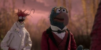 Movie still from “Muppets Haunted Mansion” (2021), directed by Kirk R. Thatcher – A muppet wearing a suit and tie with a hat on top of his head; Close Up shot, Over the shoulder angle