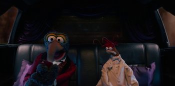 Movie still from “Muppets Haunted Mansion” (2021), directed by Kirk R. Thatcher – A couple of puppets sitting next to each other on a couch; Medium shot, High angle