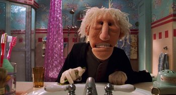 Movie still from “Muppets from Space” (1999), directed by Tim Hill – A person with a wig and a beard sitting at a sink; Close Up shot, Low angle