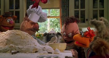 Movie still from “Muppets from Space” (1999), directed by Tim Hill – A group of people sitting at a table with food; Medium shot, Low angle