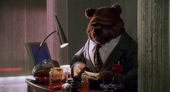Movie still from “Muppets from Space” (1999), directed by Tim Hill – A teddy bear sitting at a table eating a sandwich; Medium shot, Low angle