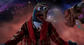 Movie still from “Muppets from Space” (1999), directed by Tim Hill – A person wearing a bird costume in front of a space background; Medium shot, Low angle