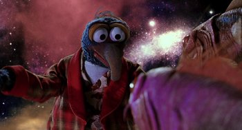 Movie still from “Muppets from Space” (1999), directed by Tim Hill – A bird character wearing a hat and a jacket in front of a space background; Medium shot, Over the shoulder angle