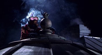 Movie still from “Muppets from Space” (1999), directed by Tim Hill – A person with a smoking pipe on a train car; Medium shot, Low angle