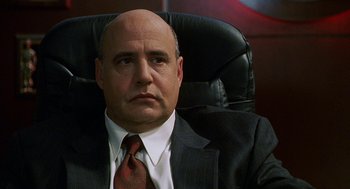 Movie still from “Muppets from Space” (1999), directed by Tim Hill – A man in a suit and tie sitting in an office chair; Close Up shot, Over the shoulder angle