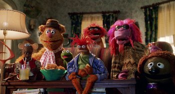 Movie still from “Muppets from Space” (1999), directed by Tim Hill – A group of muppets sitting next to each other on top of a wooden table; Wide shot, High angle