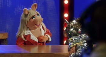 Movie still from “Muppets from Space” (1999), directed by Tim Hill – A woman dressed as miss piggy sitting at a table; Medium shot, Over the shoulder angle