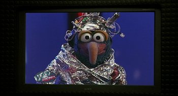 Movie still from “Muppets from Space” (1999), directed by Tim Hill – A television screen with a muppet wearing a silver costume; Close Up shot, Low angle
