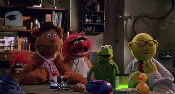 Movie still from “Muppets from Space” (1999), directed by Tim Hill – A group of stuffed animals sitting on top of a wooden table; Wide shot, High angle
