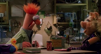 Movie still from “Muppets from Space” (1999), directed by Tim Hill – A red haired muppet sitting at a table with a box of napkins; Medium shot, Low angle
