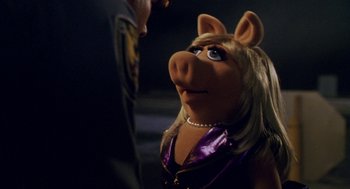 Movie still from “Muppets from Space” (1999), directed by Tim Hill – A woman in a purple dress and a pink and white pig head; Close Up shot, Over the shoulder angle