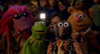 Movie still from “Muppets from Space” (1999), directed by Tim Hill – A group of people that are standing up with puppets; Medium shot, Low angle