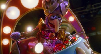 Movie still from “Muppets from Space” (1999), directed by Tim Hill – A muppet wearing a crown sitting in a box; Medium shot, Low angle