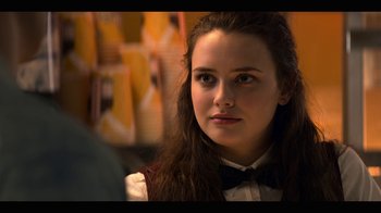 Movie still from “13 Reasons Why” (2017), created by Brian Yorkey – A young woman wearing a bow tie looking at the camera; Close Up shot, Over the shoulder angle