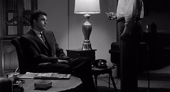 Movie still from “Murder by Contract” (1958), directed by Irving Lerner – Two men sitting in front of a lamp in a room; Medium shot, Low angle