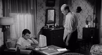 Movie still from “Murder by Contract” (1958), directed by Irving Lerner – A man sitting at a table in front of a laptop computer; Medium shot, High angle