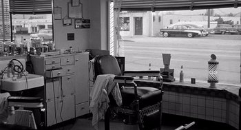 Movie still from “Murder by Contract” (1958), directed by Irving Lerner – A barber chair in front of a window with a car in the background; Wide shot, High angle