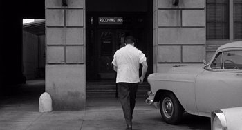 Movie still from “Murder by Contract” (1958), directed by Irving Lerner – A black and white photo of a man walking down the street; Wide shot, High angle