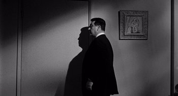 Movie still from “Murder by Contract” (1958), directed by Irving Lerner – A black and white photo of a man in a suit; Medium shot, Low angle