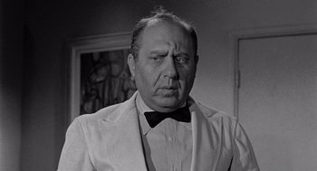 Movie still from “Murder by Contract” (1958), directed by Irving Lerner – An old black and white photo of a man wearing a suit and bow tie; Close Up shot, Over the shoulder angle