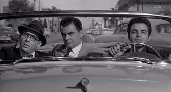 Movie still from “Murder by Contract” (1958), directed by Irving Lerner – A black - and - white photo of a man in the back of a car; Medium shot, Over the shoulder angle