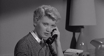 Movie still from “Murder by Contract” (1958), directed by Irving Lerner – A woman talking on a phone while sitting at a desk; Close Up shot, High angle