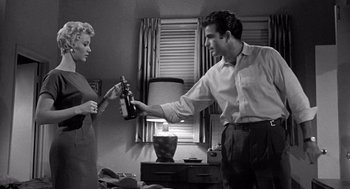 Movie still from “Murder by Contract” (1958), directed by Irving Lerner – A man and a woman are holding wine bottles; Medium shot, Low angle