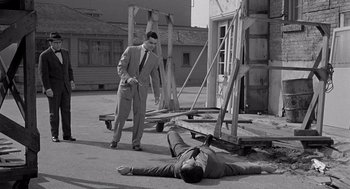 Movie still from “Murder by Contract” (1958), directed by Irving Lerner – A man standing over another man laying on the ground; Wide shot, High angle