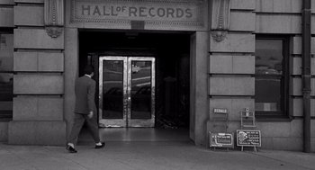 Movie still from “Murder by Contract” (1958), directed by Irving Lerner – A man walking in front of an entrance to a record store; Wide shot, Low angle