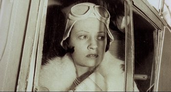 Movie still from “Murder on the Orient Express” (1974), directed by Sidney Lumet – An old photo of a woman wearing a hat and goggles; Close Up shot, Low angle