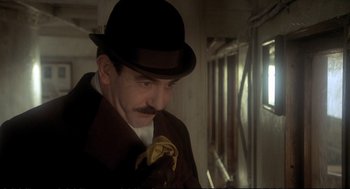 Movie still from “Murder on the Orient Express” (1974), directed by Sidney Lumet – A man with a mustache holding onto a banana peel; Close Up shot, Low angle