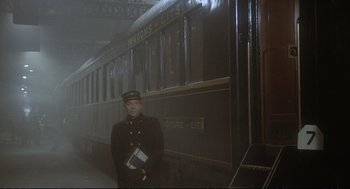 Movie still from “Murder on the Orient Express” (1974), directed by Sidney Lumet – A man in uniform standing in front of a train; Wide shot, Low angle