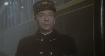 Movie still from “Murder on the Orient Express” (1974), directed by Sidney Lumet – A man in a uniform is standing in a dark room; Close Up shot, Low angle
