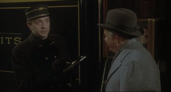 Movie still from “Murder on the Orient Express” (1974), directed by Sidney Lumet – A man wearing a hat and a uniform talking to another man in a uniform; Medium shot, Over the shoulder angle