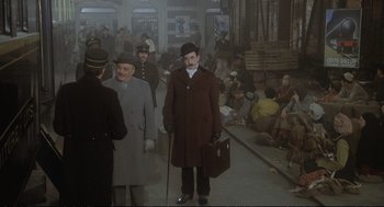 Movie still from “Murder on the Orient Express” (1974), directed by Sidney Lumet – A man in a hat and coat standing on a train platform; Wide shot, High angle