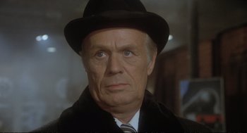 Movie still from “Murder on the Orient Express” (1974), directed by Sidney Lumet – An older man wearing a black hat and a black coat; Close Up shot, Over the shoulder angle