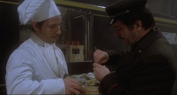 Movie still from “Murder on the Orient Express” (1974), directed by Sidney Lumet – A man in a chef's outfit is holding a knife and a plate; Close Up shot, Low angle