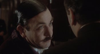 Movie still from “Murder on the Orient Express” (1974), directed by Sidney Lumet – A person wearing a suit and tie; Close Up shot, Over the shoulder angle