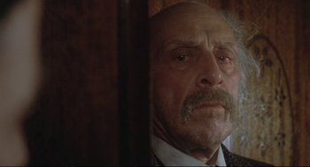 Movie still from “Murder on the Orient Express” (1974), directed by Sidney Lumet – An old man with a beard and a mustache looking sad; Close Up shot, Over the shoulder angle
