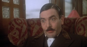 Movie still from “Murder on the Orient Express” (1974), directed by Sidney Lumet – A person sitting on a couch; Close Up shot, Low angle